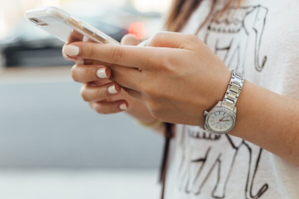 A woman holding a phone and chatting using both hands