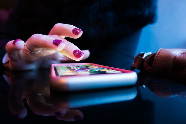 Woman with pink fingernails on smartphone